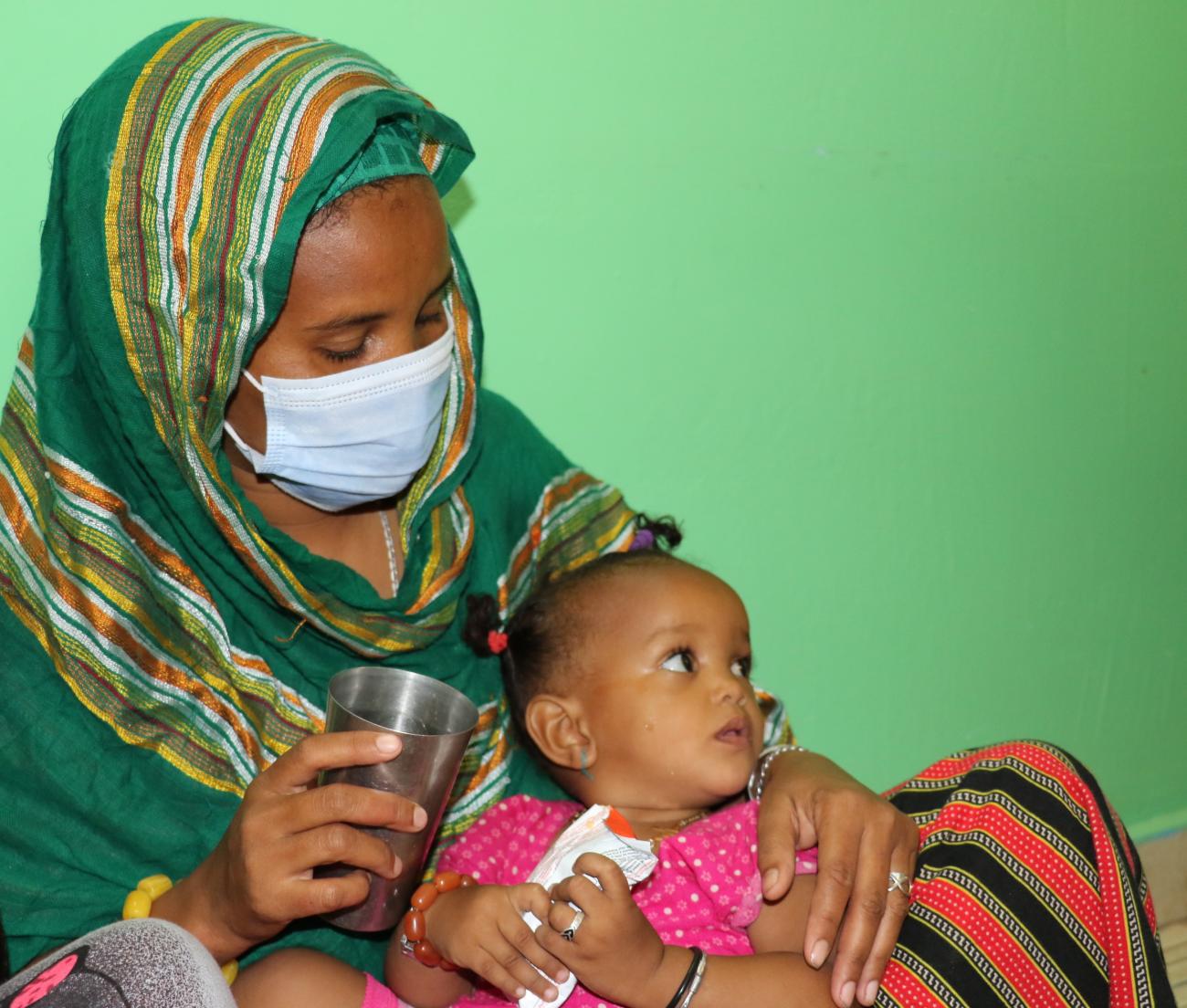 Hawa dans les bras de la mère. Elle prend sa ration de Plumpy Nut. - ©UNICEF/Djibouti/2020/Oulmi